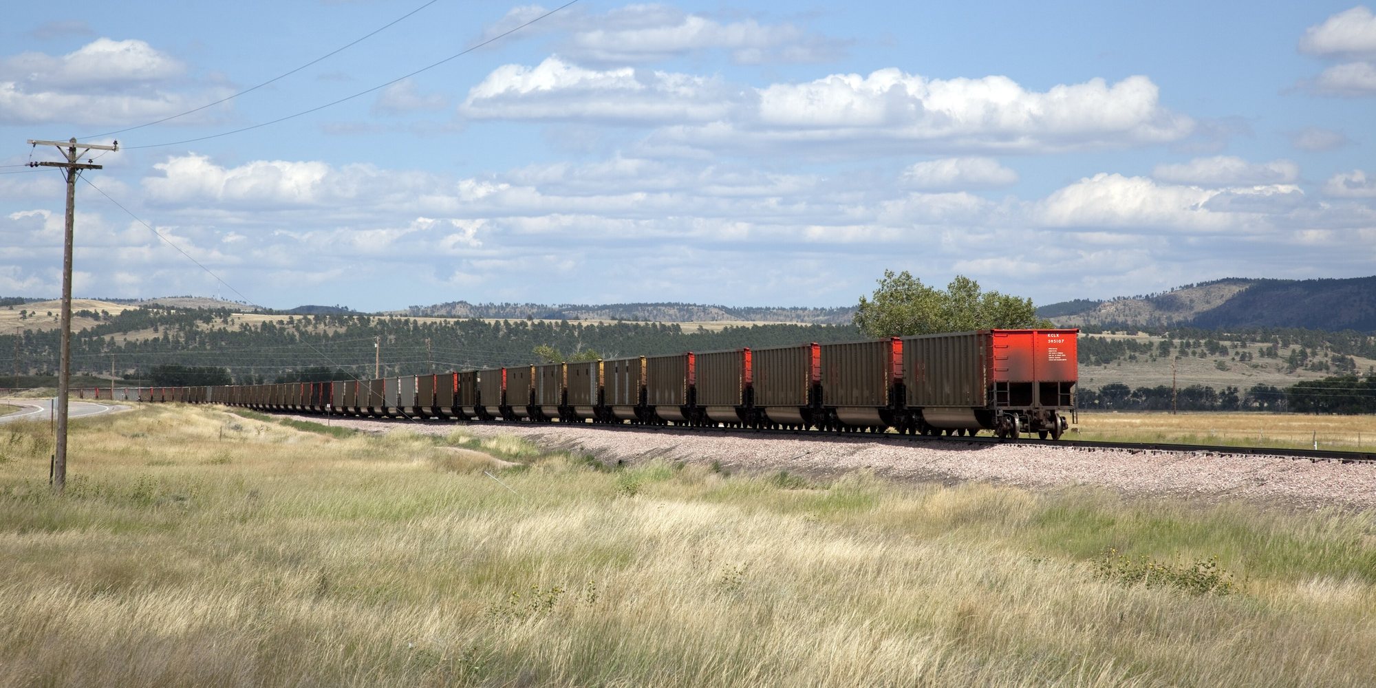 A freight train on timber railway ties beside a wooden utility pole, rural South Dakota